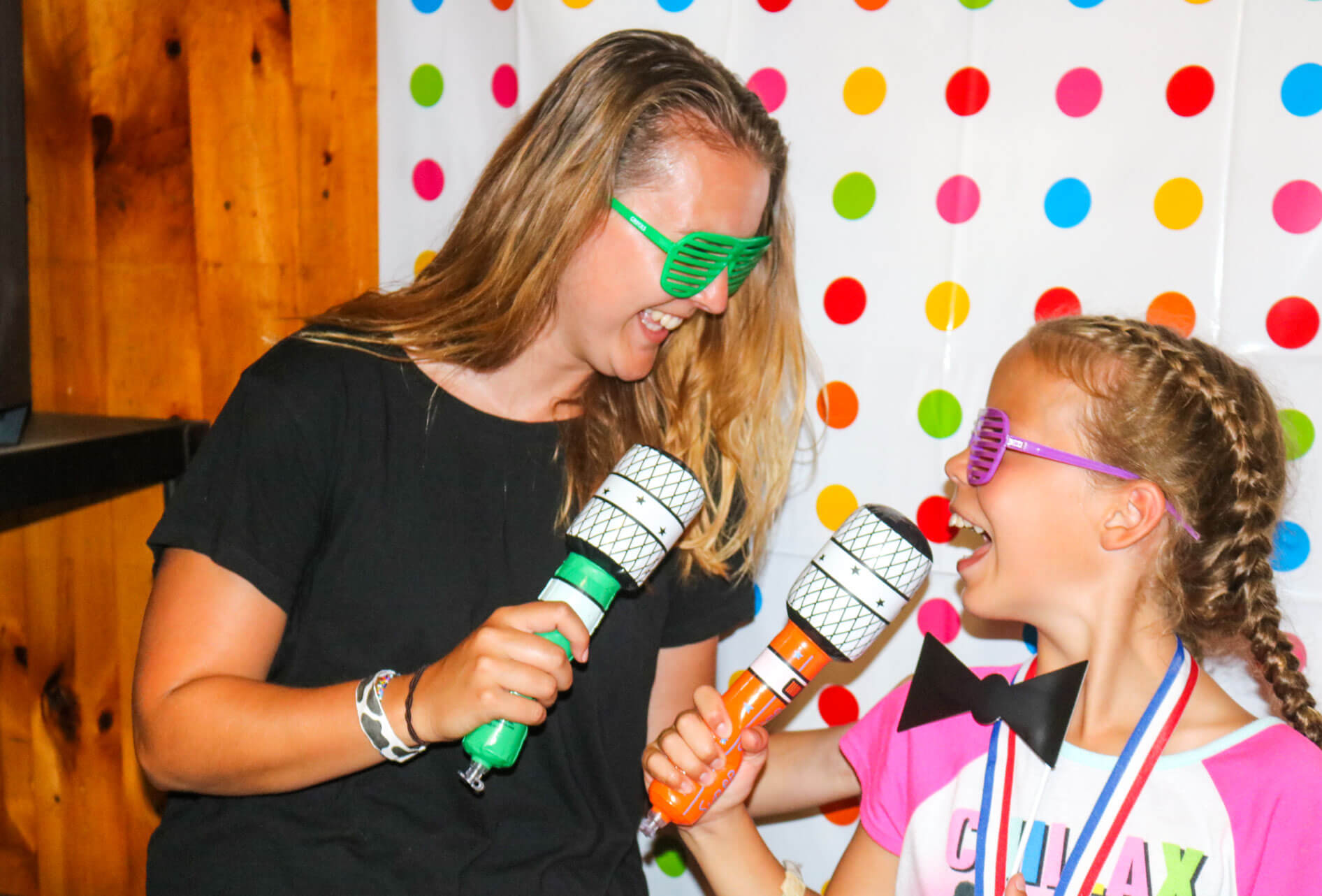 Counselor and camper sing into colorful microphones