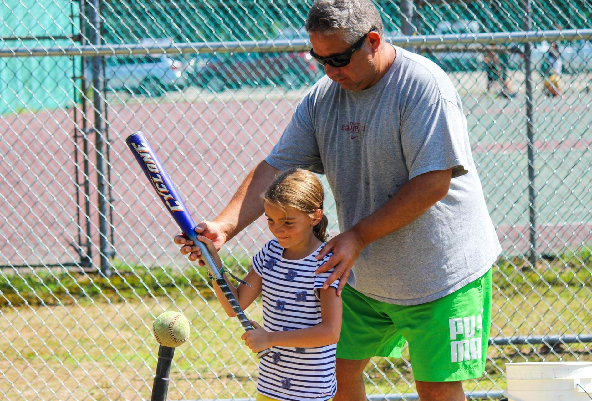 Staff helps young camper with softball