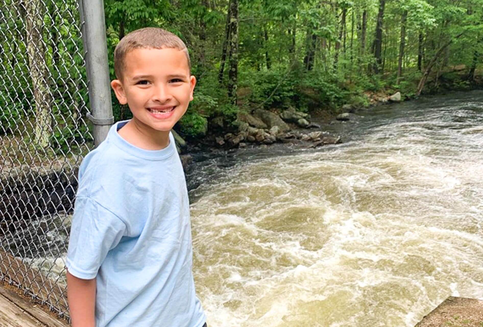 Young camper stands near river