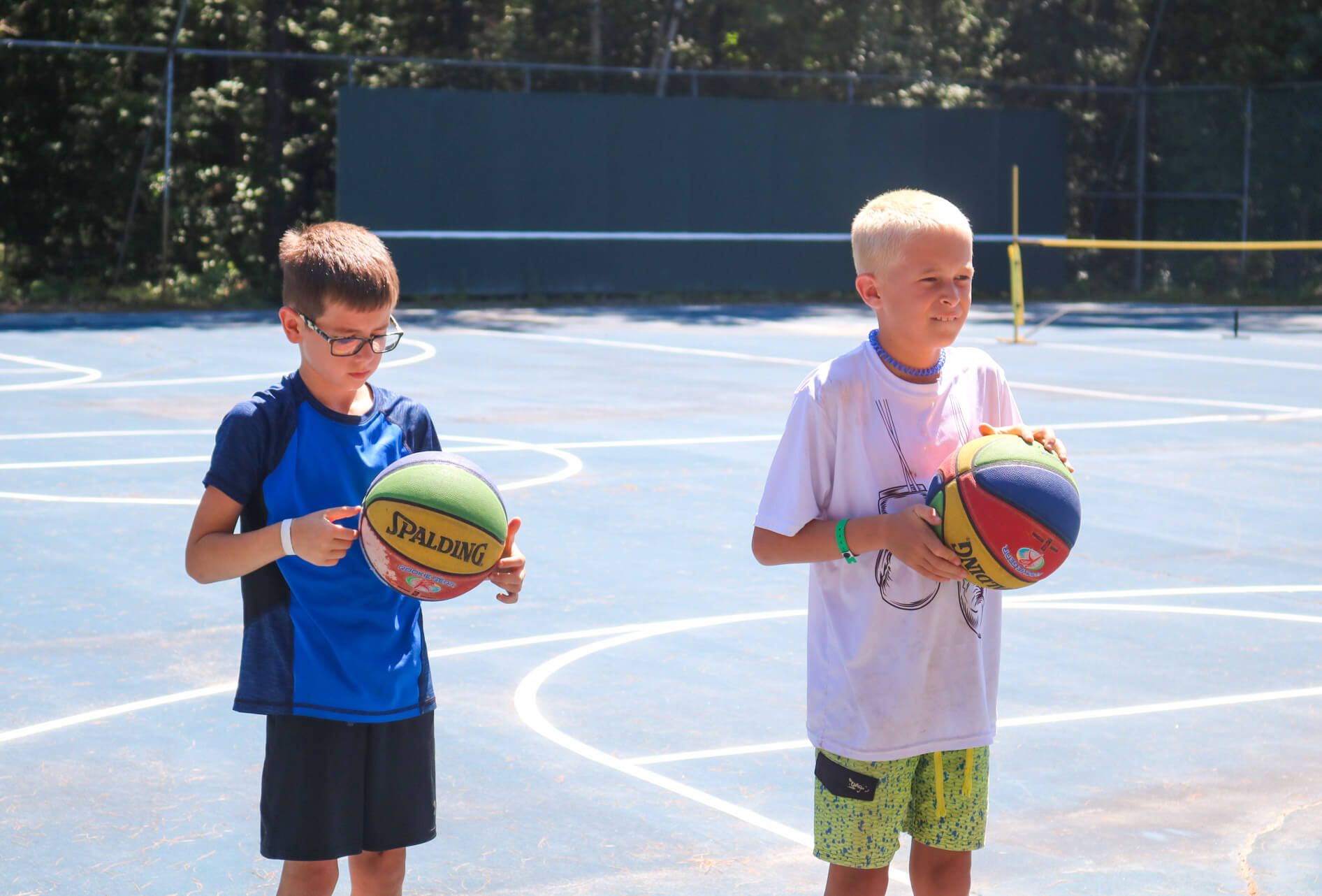 Two young campers hold colored basketballs